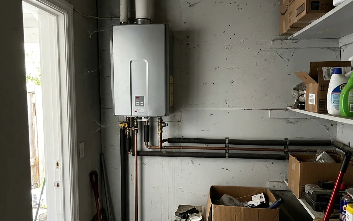Wall-mounted tankless water heater with copper lines in a utility closet