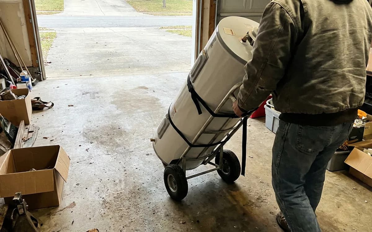 New water heater being wheeled into a garage on a hand truck