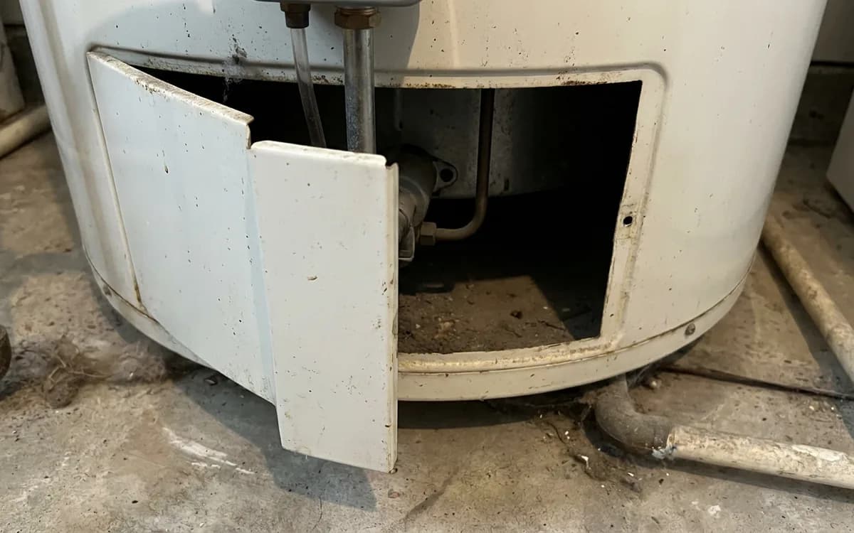 Burner compartment access panel at the base of a gas water heater