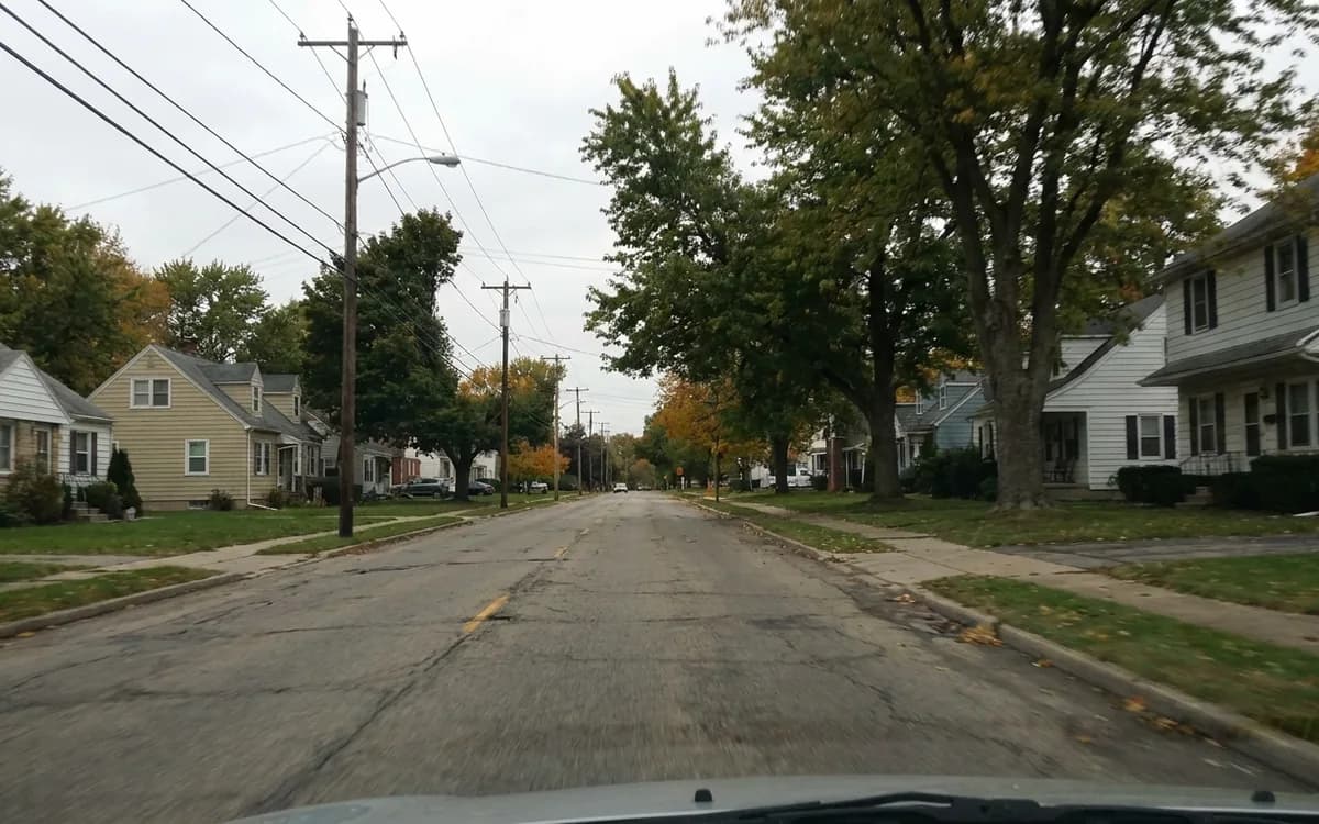 Suburban road running between residential neighborhoods under open sky
