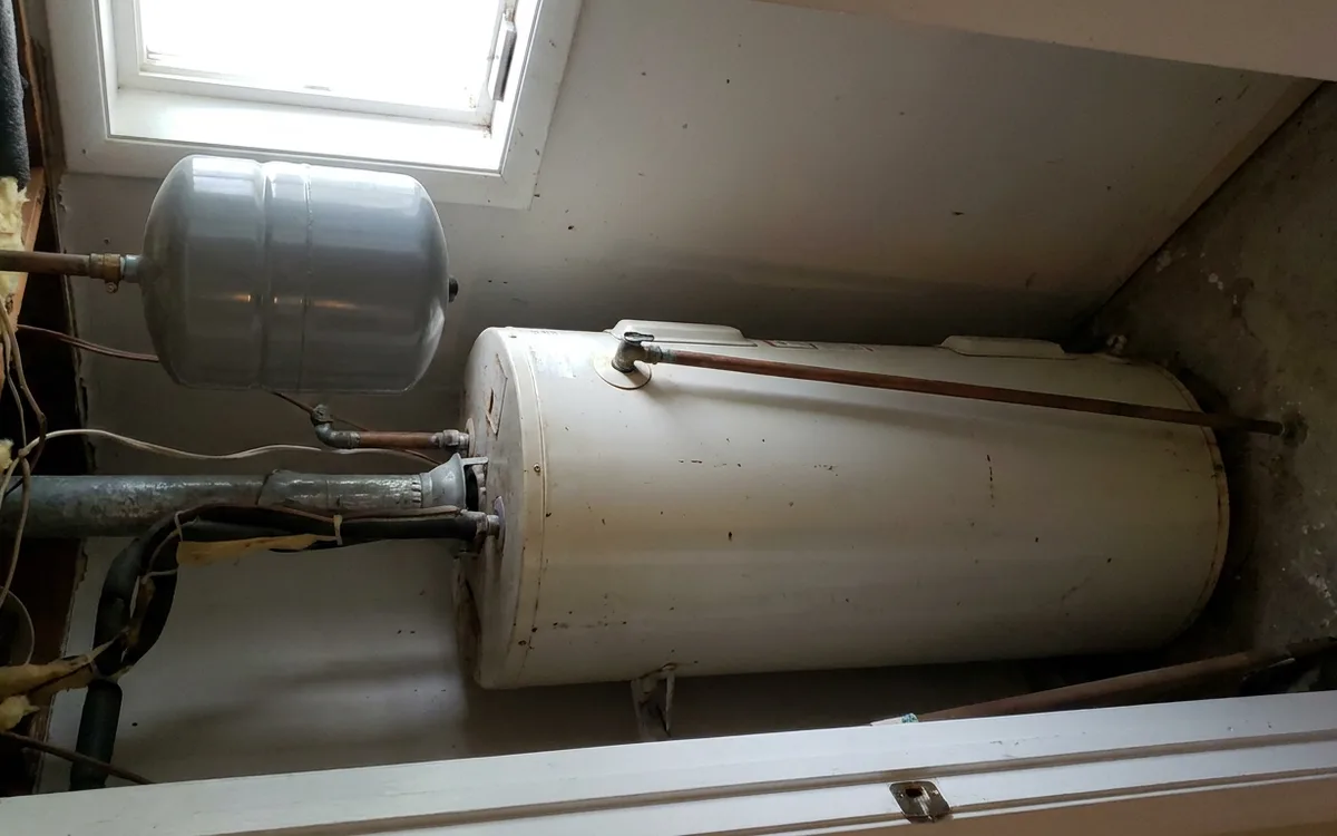 Expansion tank and temperature-pressure discharge line above a water heater