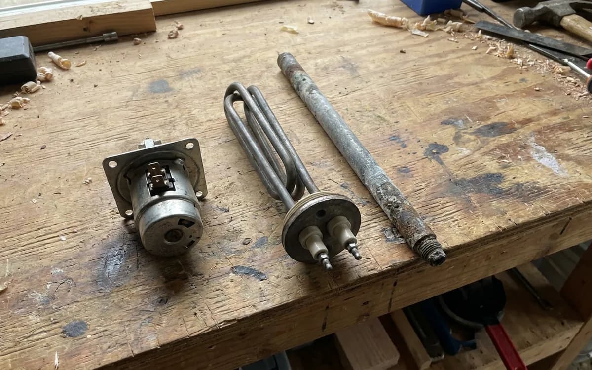 Replacement thermostat, heating element and anode rod arranged on a workbench